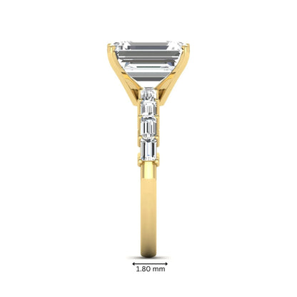 Emerald cut lab grown diamond engagement ring with baguette side diamonds in a four-prong solitaire accent setting and yellow gold tone band.