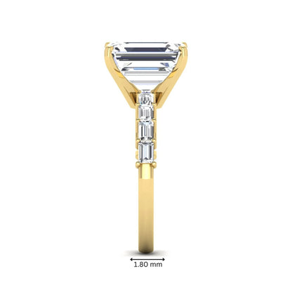 Emerald cut lab grown diamond engagement ring with baguette side diamonds in a four-prong solitaire accent setting and yellow gold tone band.