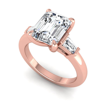 Emerald cut lab grown diamond three-stone engagement ring featuring tapered baguette side diamonds in a classic four-prong rose gold style setting.