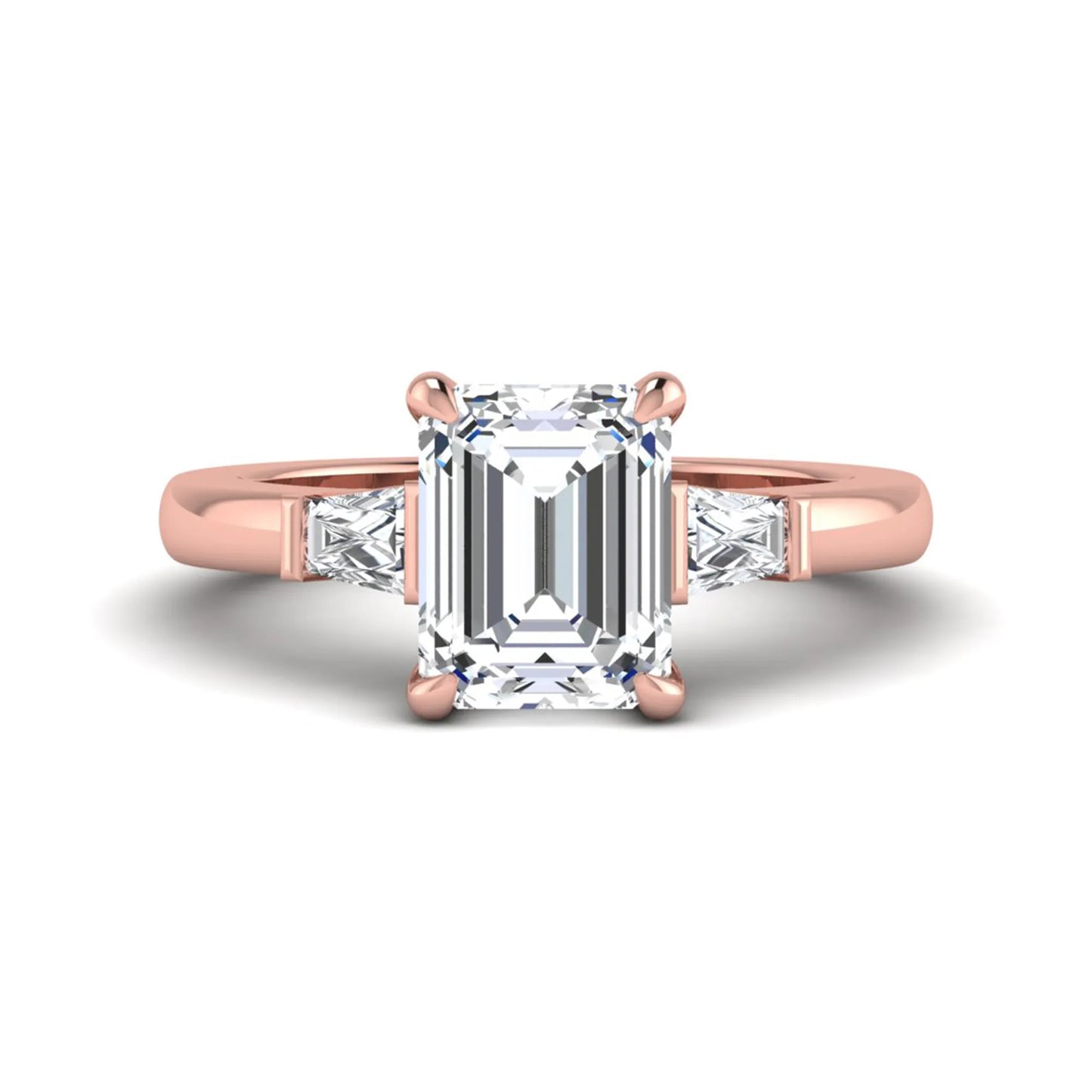 Emerald cut lab grown diamond three-stone engagement ring featuring tapered baguette side diamonds in a classic four-prong rose gold style setting.