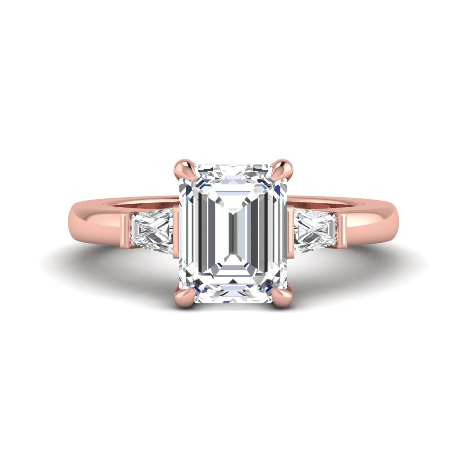 Emerald cut lab grown diamond three-stone engagement ring featuring tapered baguette side diamonds in a classic four-prong rose gold style setting.