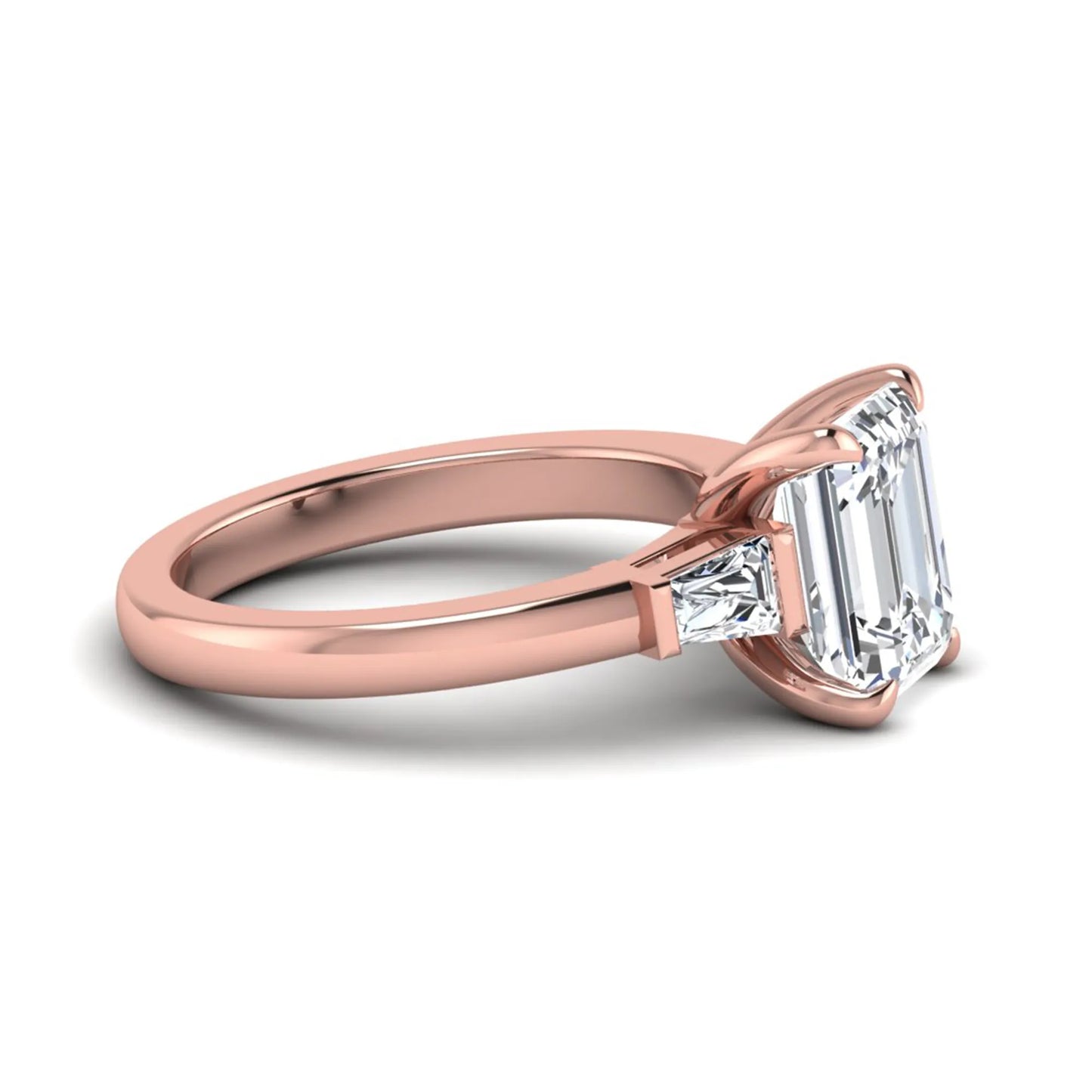Emerald cut lab grown diamond three-stone engagement ring featuring tapered baguette side diamonds in a classic four-prong rose gold style setting.