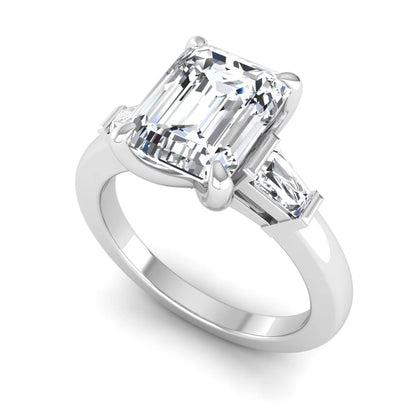 Emerald cut lab grown diamond three-stone engagement ring featuring tapered baguette side diamonds in a classic four-prong white gold style setting.