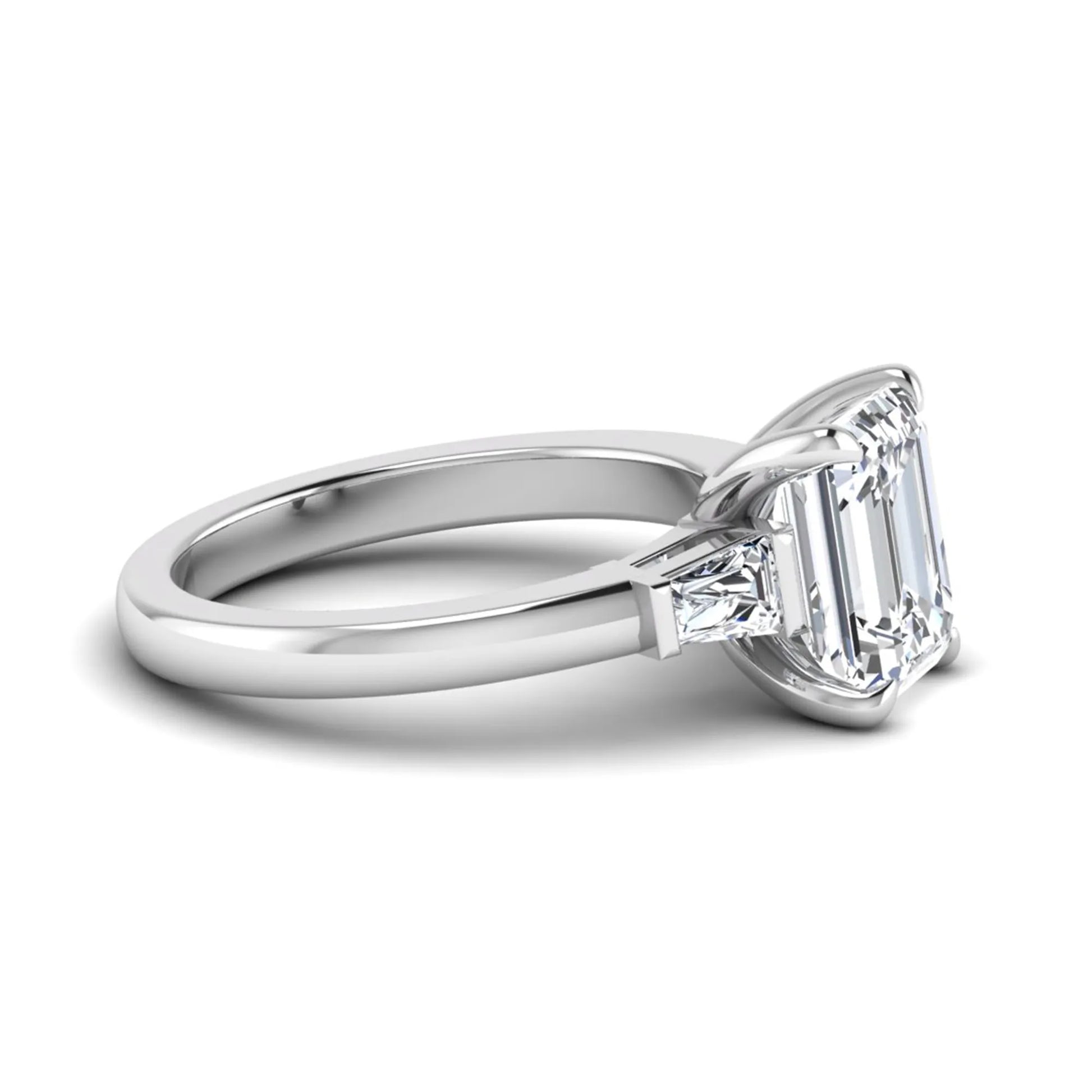 Emerald cut lab grown diamond three-stone engagement ring featuring tapered baguette side diamonds in a classic four-prong white gold style setting.