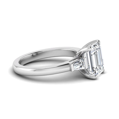 Emerald cut lab grown diamond three-stone engagement ring featuring tapered baguette side diamonds in a classic four-prong white gold style setting.