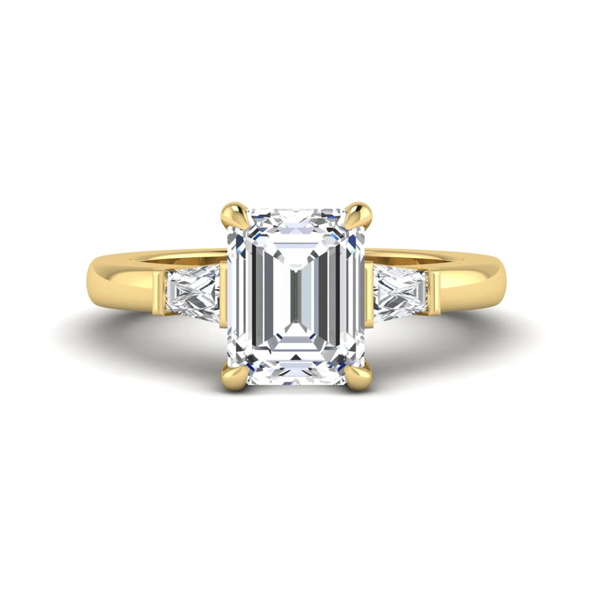 Emerald cut lab grown diamond three-stone engagement ring featuring tapered baguette side diamonds in a classic four-prong yellow gold style setting.