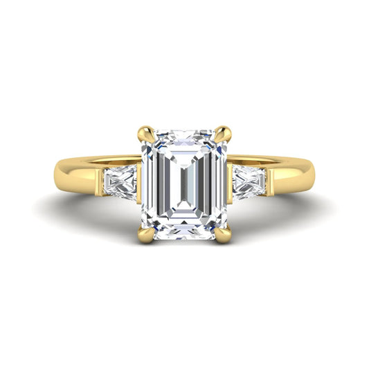 Emerald cut lab grown diamond three-stone engagement ring featuring tapered baguette side diamonds in a classic four-prong yellow gold style setting.