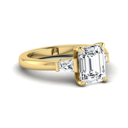 Emerald cut lab grown diamond three-stone engagement ring featuring tapered baguette side diamonds in a classic four-prong yellow gold style setting.