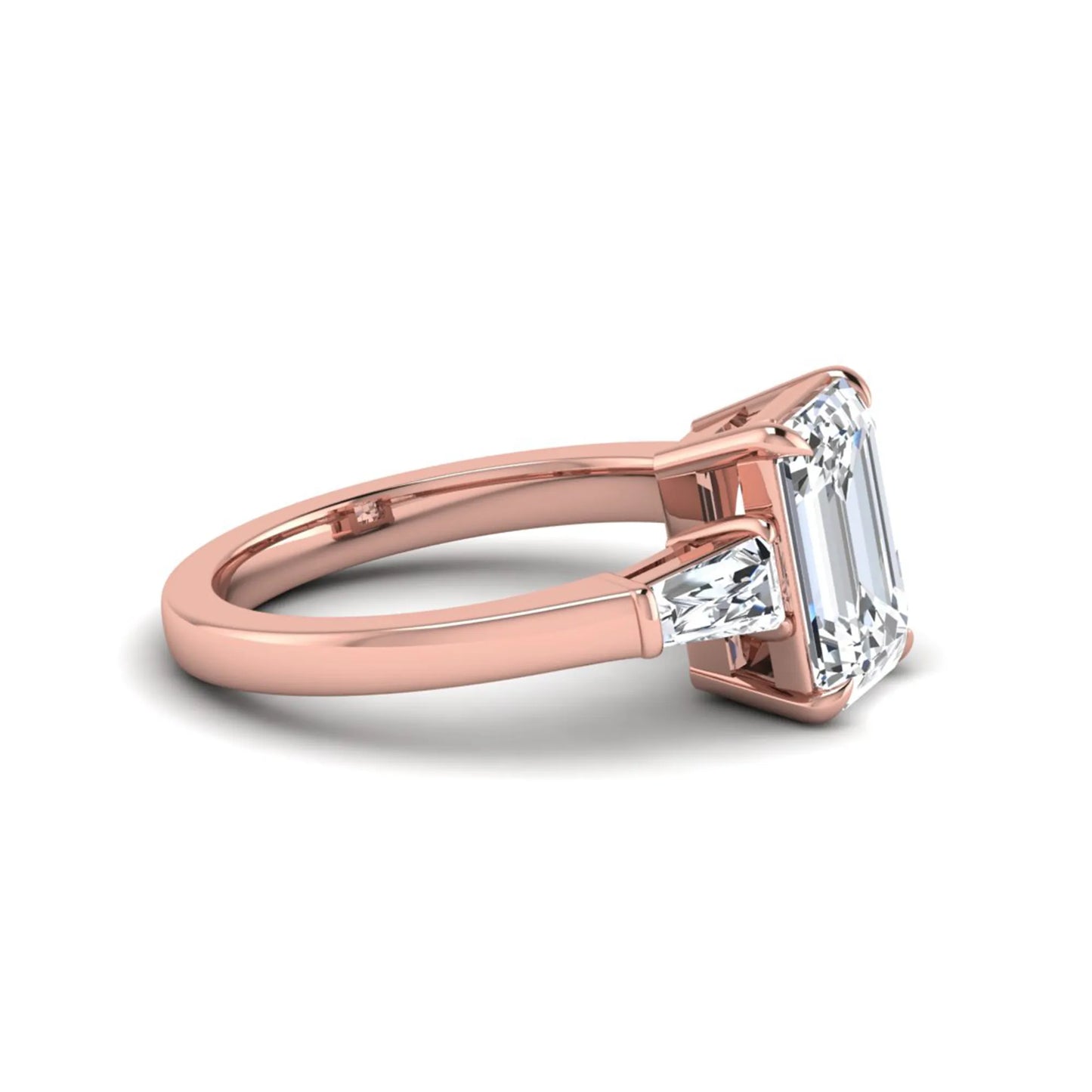 Emerald three stone prong set lab grown diamond engagement ring featuring a 3.00 carat emerald cut center diamond with tapered baguette side diamonds in rose gold finish.