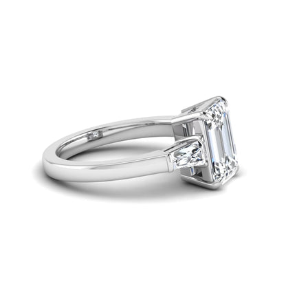 Emerald three stone prong set lab grown diamond engagement ring featuring a 3.00 carat emerald cut center diamond with tapered baguette side diamonds in white gold finish.