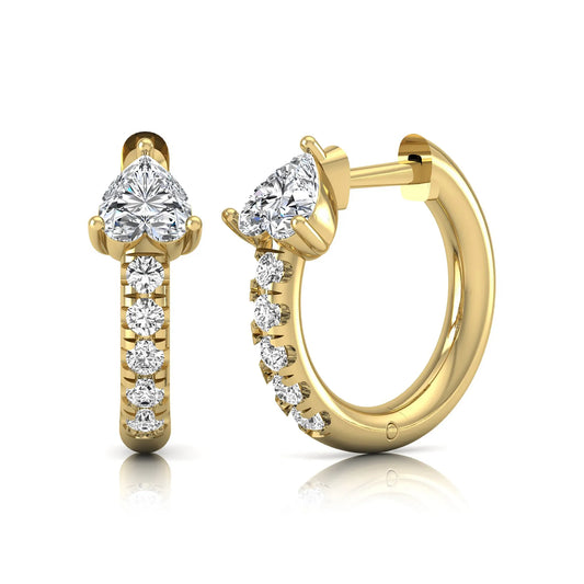 Heart cut lab grown diamond huggie hoop earrings featuring a three prong basket set center diamond with round brilliant pavé diamonds on a yellow gold hoop.