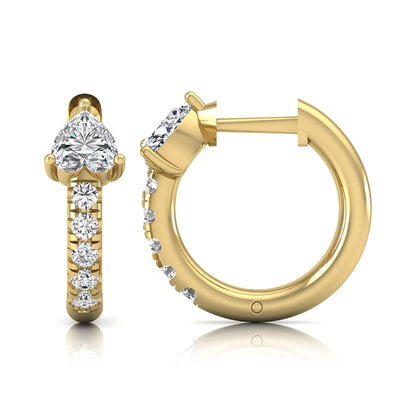 Heart cut lab grown diamond huggie hoop earrings featuring a three prong basket set center diamond with round brilliant pavé diamonds on a yellow gold hoop.