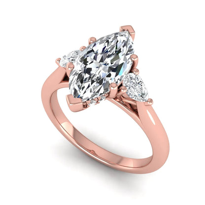 Marquise cut lab grown diamond three stone engagement ring with prong setting, round and pear side diamonds, rose gold tone shown for design reference.