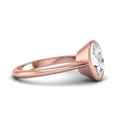 Oval cut lab grown diamond solitaire engagement ring in a bezel setting with a rose gold tone minimalist band.