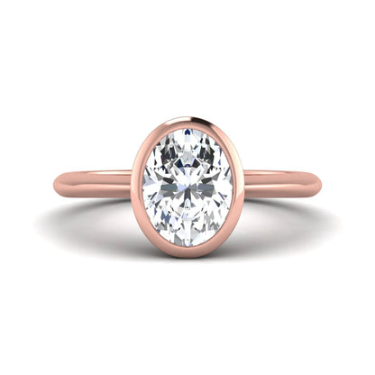 Oval cut lab grown diamond solitaire engagement ring in a bezel setting with a rose gold tone minimalist band.