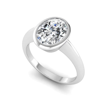 Oval cut lab grown diamond solitaire engagement ring in a bezel setting with a white gold tone minimalist band.