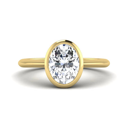 Oval cut lab grown diamond solitaire engagement ring in a bezel setting with a yellow gold tone minimalist band.