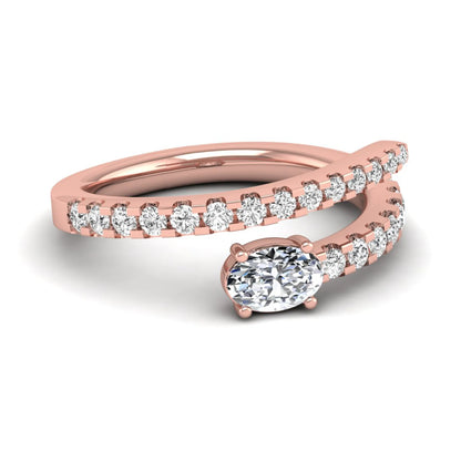 Oval cut lab grown diamond bypass engagement ring with round pavé accent diamonds in a four-prong setting in rose gold