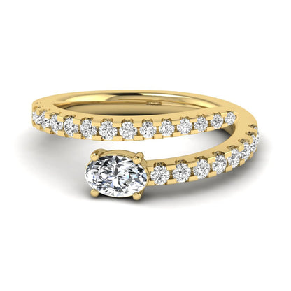 Oval cut lab grown diamond bypass engagement ring with round pavé accent diamonds in a four-prong setting in yellow gold