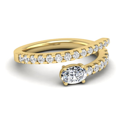 Oval cut lab grown diamond bypass engagement ring with round pavé accent diamonds in a four-prong setting in yellow gold
