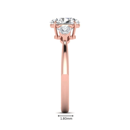 Oval cut lab grown diamond three stone engagement ring with pear cut side diamonds and prong setting in rose gold tone.