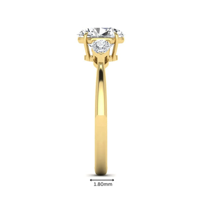 Oval cut lab grown diamond three stone engagement ring with pear cut side diamonds and prong setting in yellow gold tone.