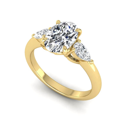 Oval cut three stone lab grown diamond engagement ring in yellow gold featuring a 1.31 carat IGI certified center diamond with pear cut side diamonds.