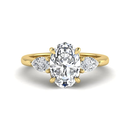 Oval cut three stone lab grown diamond engagement ring in yellow gold featuring a 1.31 carat IGI certified center diamond with pear cut side diamonds.