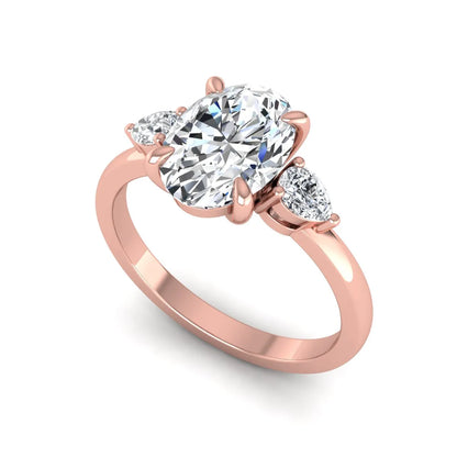 Oval cut lab grown diamond three stone engagement ring with pear side diamonds in rose gold.