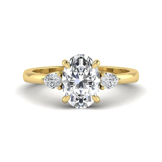 Oval cut lab grown diamond three stone engagement ring with pear side diamonds in yellow gold.