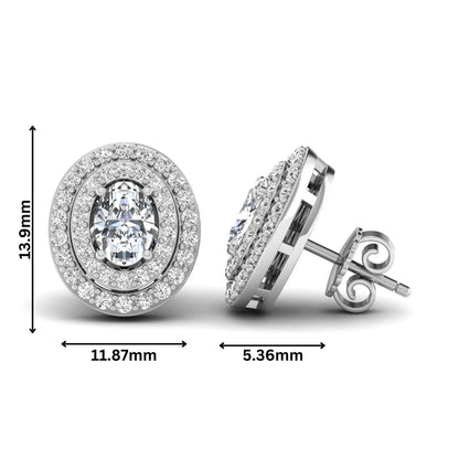 Oval cut lab grown diamond stud earrings featuring a double halo of round cut diamonds, prong setting, push back closure, and white gold tone design.