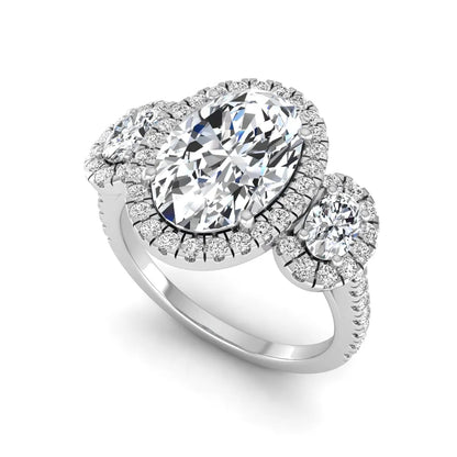Oval cut lab grown diamond three stone engagement ring featuring a halo center, halo oval side diamonds, pavé shoulders, and a polished white gold tone band.