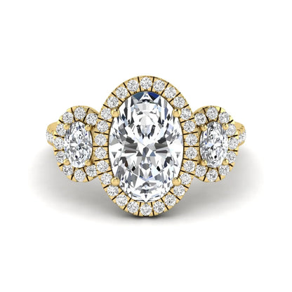 Oval cut lab grown diamond three stone engagement ring featuring a halo center, halo oval side diamonds, pavé shoulders, and a polished yellow gold tone band.