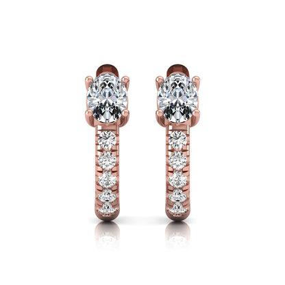 Oval cut lab grown diamond huggie hoop earrings featuring a four prong basket set center diamond with graduated round brilliant pavé diamonds on a rose gold hoop.