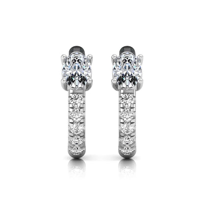 Oval cut lab grown diamond huggie hoop earrings featuring a four prong basket set center diamond with graduated round brilliant pavé diamonds on a white gold hoop.