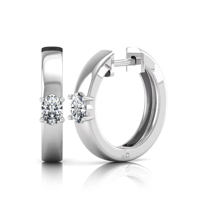 Oval cut lab grown diamond huggie hoop earrings featuring a classic four prong setting and hinged snap closure shown in white gold tone with a polished finish.