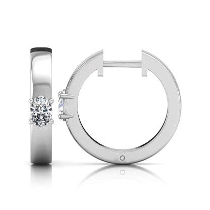 Oval cut lab grown diamond huggie hoop earrings featuring a classic four prong setting and hinged snap closure shown in white gold tone with a polished finish.