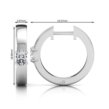 Oval cut lab grown diamond huggie hoop earrings featuring a classic four prong setting and hinged snap closure shown in white gold tone with a polished finish.