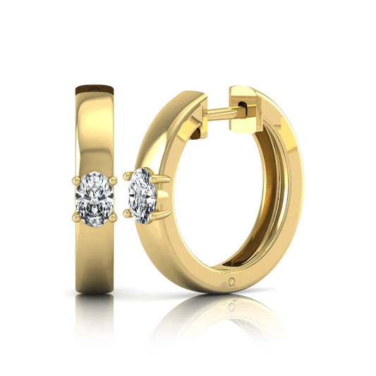 Oval cut lab grown diamond huggie hoop earrings featuring a classic four prong setting and hinged snap closure shown in yellow gold tone with a polished finish.
