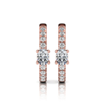 Oval and round lab grown diamond pavé huggie hoop earrings featuring a four prong oval center diamond with graduated shared prong round diamond accents in rose gold.