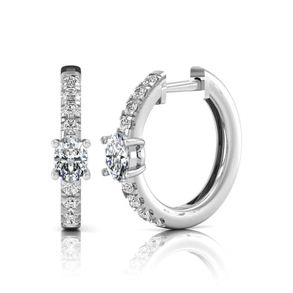 Oval and round lab grown diamond pavé huggie hoop earrings featuring a four prong oval center diamond with graduated shared prong round diamond accents in white gold.