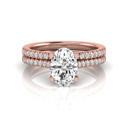 Oval cut lab grown diamond solitaire bridal ring set featuring a four-prong center diamond with pavé diamond engagement ring and matching pavé wedding band in rose gold tone.
