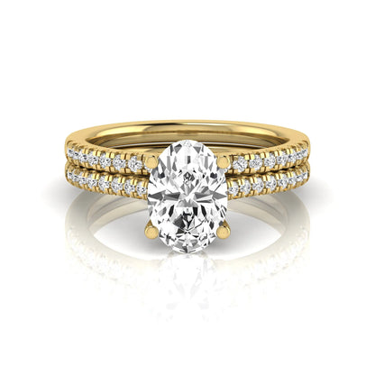 Oval cut lab grown diamond solitaire bridal ring set featuring a four-prong center diamond with pavé diamond engagement ring and matching pavé wedding band in yellow gold tone.