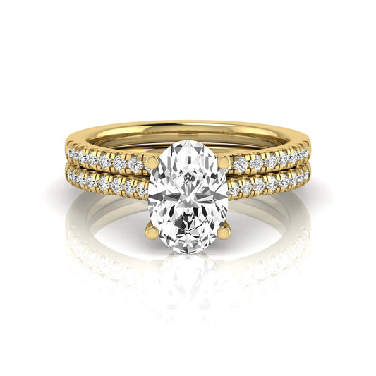 Oval cut lab grown diamond solitaire bridal ring set featuring a four-prong center diamond with pavé diamond engagement ring and matching pavé wedding band in yellow gold tone.