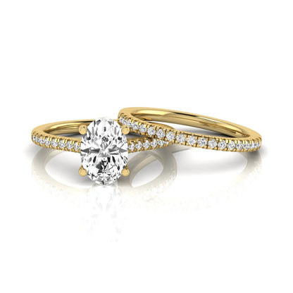 Oval cut lab grown diamond solitaire bridal ring set featuring a four-prong center diamond with pavé diamond engagement ring and matching pavé wedding band in yellow gold tone.