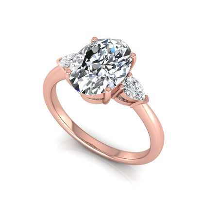 Oval three stone lab grown diamond engagement ring featuring a 1.86 carat IGI certified oval cut center diamond with pear cut side diamonds in a rose gold design.