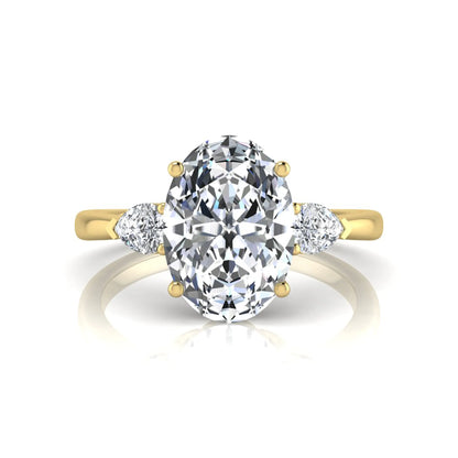 Oval three stone lab grown diamond engagement ring featuring a 1.86 carat IGI certified oval cut center diamond with pear cut side diamonds in a yellow gold design.