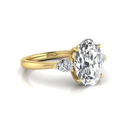 Oval three stone lab grown diamond engagement ring featuring a 1.86 carat IGI certified oval cut center diamond with pear cut side diamonds in a yellow gold design.