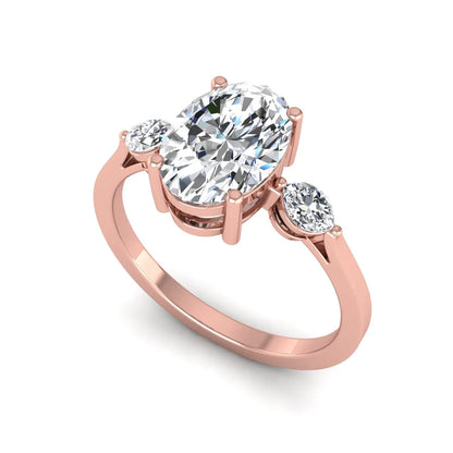 Oval cut lab grown diamond three stone engagement ring with marquise side diamonds in a prong setting featuring a rose gold tone design.