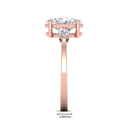 Oval cut lab grown diamond three stone engagement ring with marquise side diamonds in a prong setting featuring a rose gold tone design.